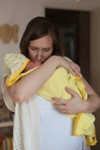 mom holding newborn baby after a bath