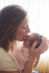 mom kissing newborn baby