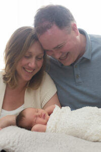 parents smiling at newborn baby