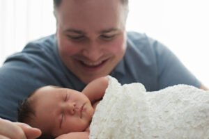 dad smiling at sleeping baby