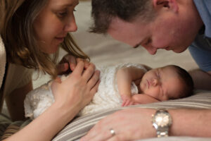 mom and dad looking at baby lovingly newborn photography session
