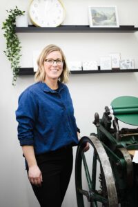 designer standing by Chandler and Price platen press in studio
