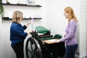 designer standing by Chandler and Price platen press in studio