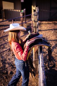 girl tacking up her horse at golden hour personalized Calgary grad session
