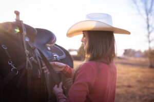 girl tacking up her horse at golden hour personalized Calgary grad session