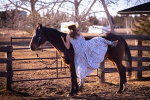 girl mounting horse bare back in long flowing dress personalized Calgary grad photo session