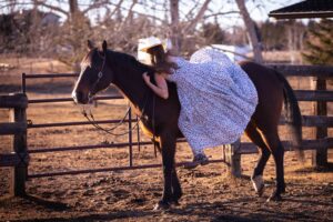 girl mounting horse bare back in long flowing dress personalized Calgary grad photo session