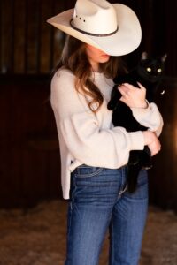 portrait of a cowgirl in her barn with cat personalized Calgary grad photo session