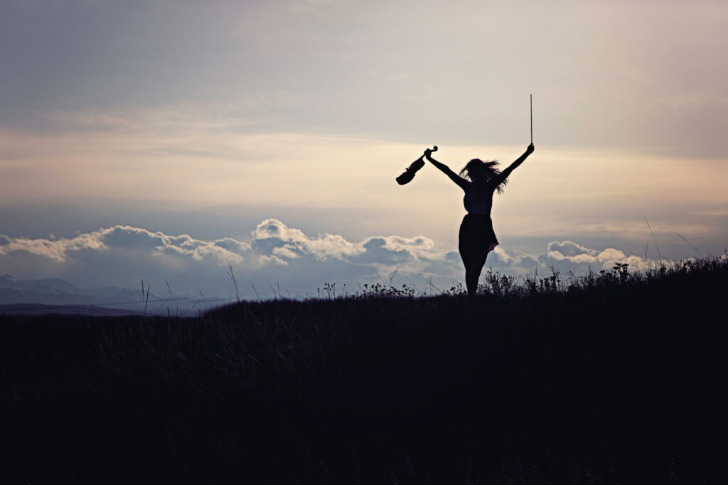 silhoutte of high school graduate celebrating with violin