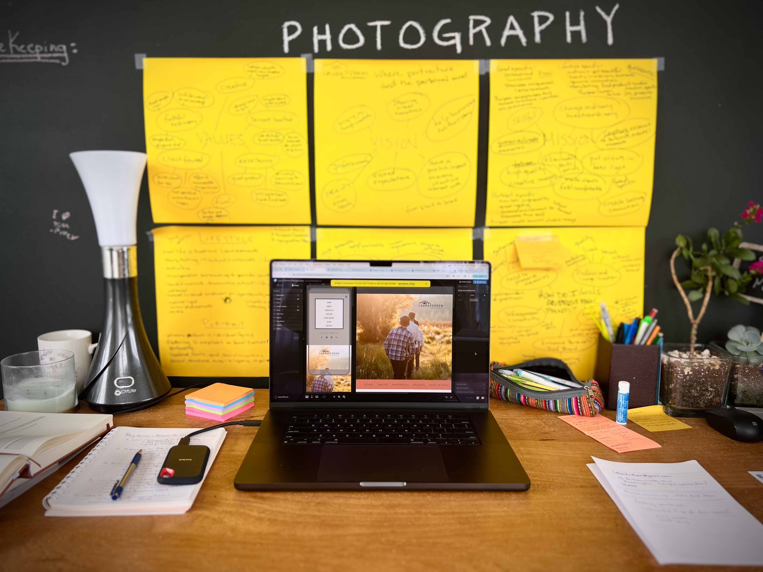 behind the scenes photo of work desk with computer and sticky notes Calgary photographer