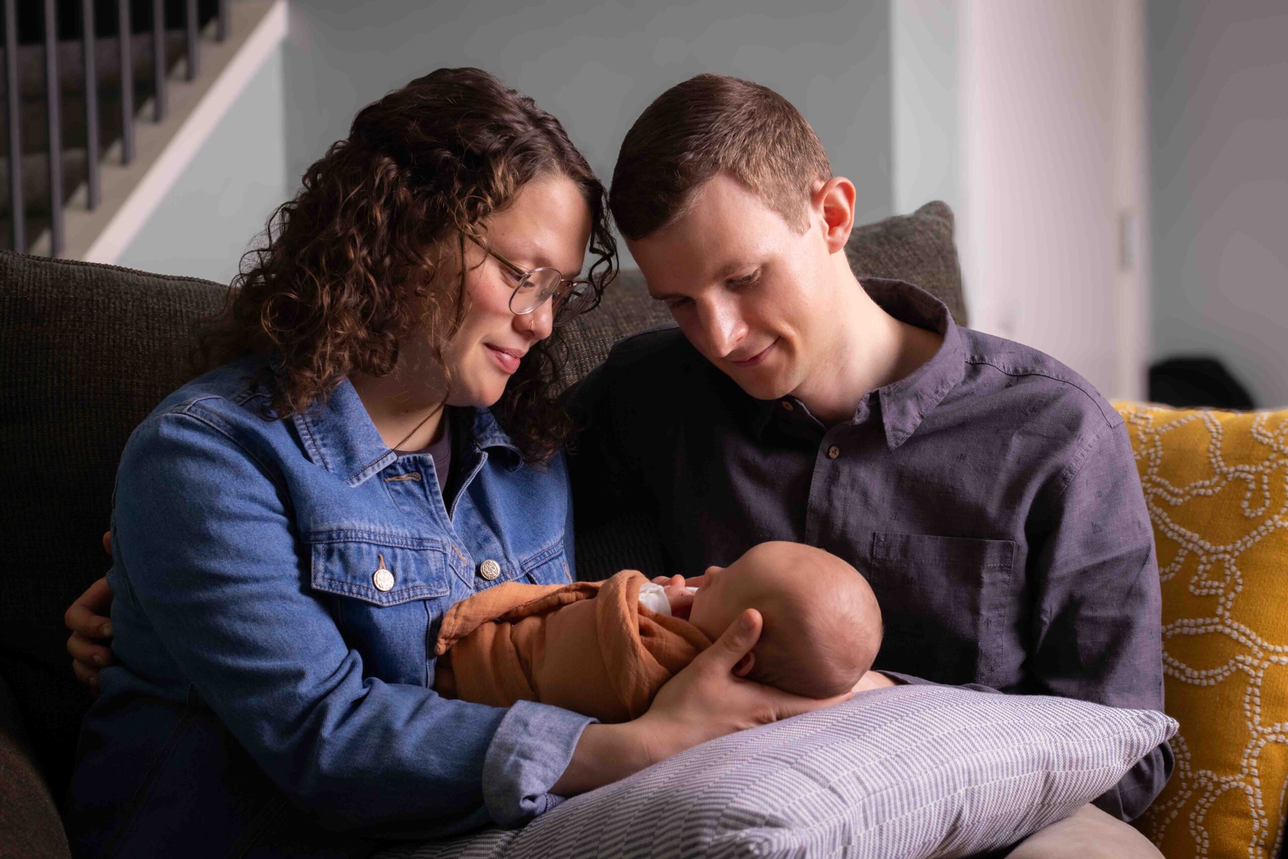 at home newborn photography session Calgary mom and dad holding newborn