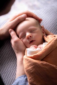 at home newborn photography session Calgary mom and dad's hands holding newborn