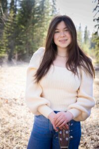 graduate posing with guitar in Griffith Woods Park Calgary