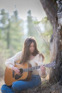 grad playing guitar in Griffith Woods Park Calgary