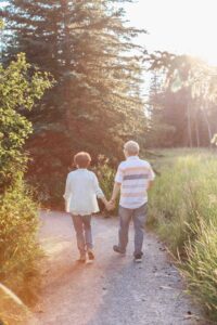 50th anniversary couple walking hand in hand into golden hour light in griffith woods calgary family photo session