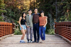 family posing on iron bridge in griffith woods park calgary family photo session