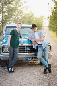 two Calgary high school grads posing in front of a restored Chevrolet truck