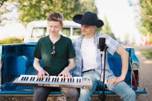 two musicians sitting in the back of a Chevy truck