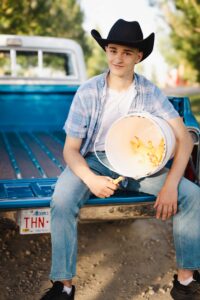 young cowboy sitting in a chevy truck with a bucket full of chickens