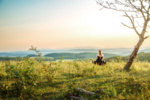 calgary high school grad sitting in field looking at foothills and rocky mountains during golden hour