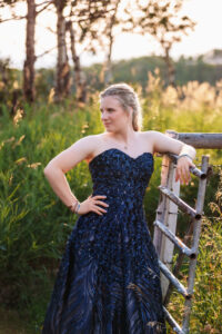 calgary high school grad sitting posing against wooden fence in farmers field