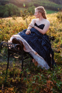 calgary high school grad sitting on wrought iron bench in field during golden hour