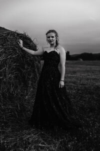 Calgary high school girl in grad dress posed next to hay bale