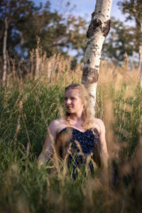 calgary high school grad sitting in field of grass during golden hour