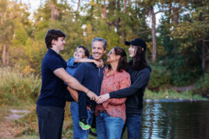 family of family hugging and smiling at fish creek park calgary alberta