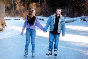Rachel and Daniel hold hands while skating on the frozen lagoon at Bowness Park, laughing as they enjoy their winter engagement session.