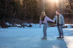 She leads him by the hand while skating around the frozen pond, with a forested backdrop adding natural beauty. She lovingly smiles back at him, while he looks admiringly at her. Both wear jeans; she has a purple sweater, and he sports a sherpa-lined jean jacket.