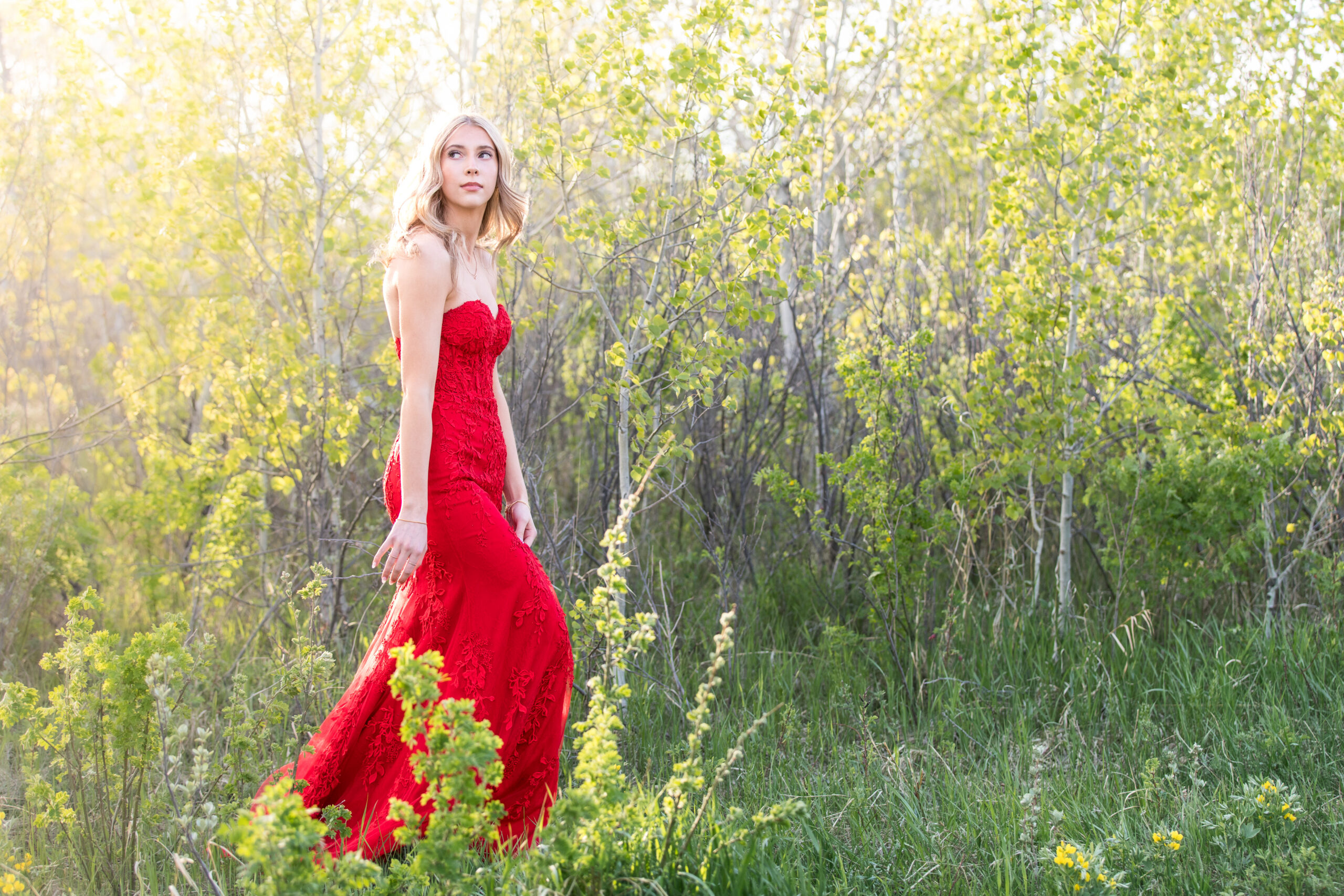 Calgary grad portrait of a graduate in a flowing red dress surrounded by trees and golden evening light