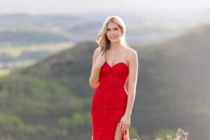 Calgary grad portrait of a graduate in a red dress standing in golden sunset light overlooking the Alberta foothills