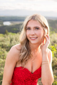 Close-up Calgary grad portrait of a graduate in a red dress with soft sunset light and mountain views in the background