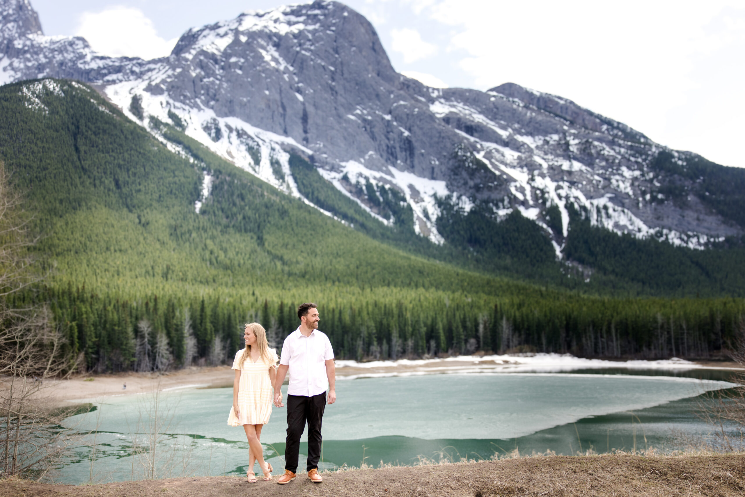 Couple holding hands beside a mountain lake in Kananaskis Country near Calgary, Alberta