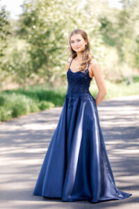 Full-length graduation portrait featuring a navy blue graduation dress photographed on graduation day.