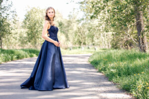 Graduate smiling during a same-day graduation photo session in a navy blue graduation dress.